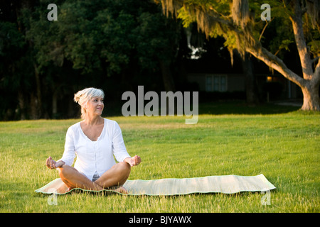 Frau mittleren Alters sitzen auf Matte praktizieren Yoga im freien Stockfoto