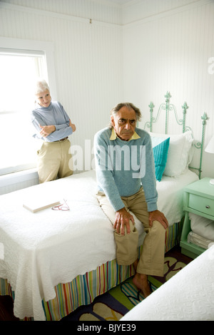 Porträt des mürrischen senior Mann sitzen Bett, senior Frau stand hinter Stockfoto