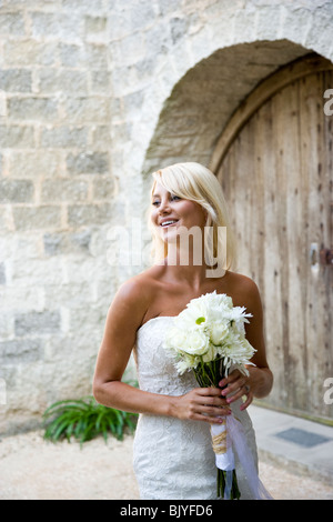 Lächelnde junge Braut hält Blumenstrauss im freien Stockfoto
