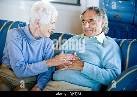 Älteres Paar auf blau gestreiften Couch sitzen Stockfoto
