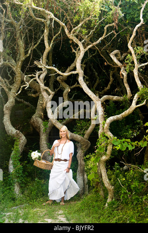 Junge blonde Frau in weißen Holding Korb mit Blumen Stockfoto