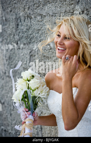 Braut hält Blumenstrauss Stein Wand gelehnt lachen Stockfoto