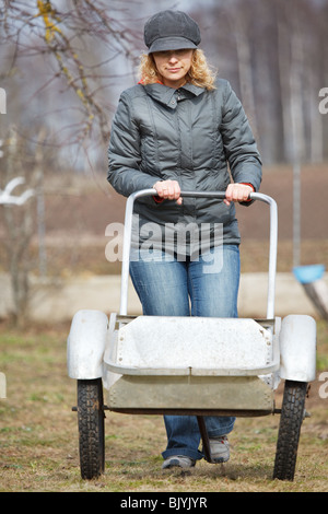 Frau, Schieben Karren in Garten, frühen Frühjahr Szene Stockfoto