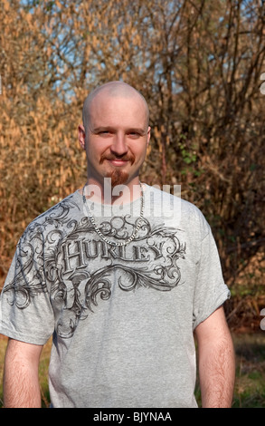 Diese vertikale Porträt eines Mitte der zwanziger Jahre kaukasischen, lächelnd im Freien im zeitigen Frühjahr. Er hat helle Haut und einem warmen Lächeln. Stockfoto