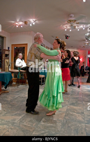 Ein älterer Mann tanzt Walzer mit einer jüngeren Frau in einem grünen Kleid im Stil der Ballsaal tanzen um gesund zu bleiben. Stockfoto