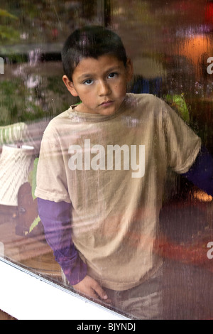 multikulturelle Multi-Kulti-9-10 Jahre Jahre Alter spanischer Junge Blick durch ein Fenster an einem regnerischen Tag. Traurige Gesicht des Kindes Herr © Myrleen Pearson Stockfoto