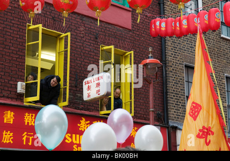 Menschen mit Blick aus den Fenstern am chinesischen Neujahrsfest in China Town, London England UK 2010 Stockfoto