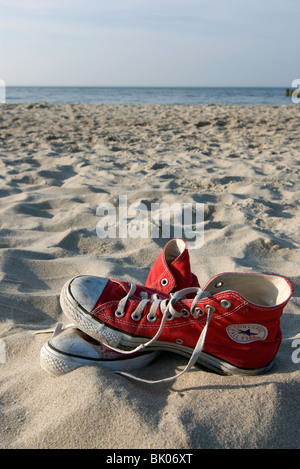 Roten Converse "Chucks" Sneakers in den Sand. Stockfoto