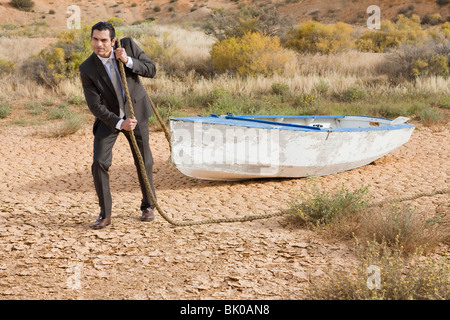 Geschäftsmann Abschleppen eine Boot in der Wüste Stockfoto