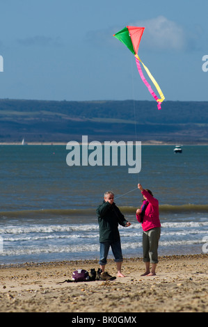 Ein paar, einen Kite am Strand in Bournemouth, windigen Tag im Frühjahr starten. Stockfoto