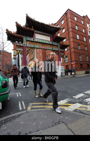 Vier chinesische Fußgänger zu Fuß entfernt von der chinesischen kaiserlichen Arch in Chinatown, Faulkner Street, Manchester, England. Stockfoto