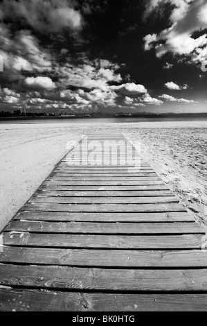 Dramatischen Blick auf einen Holzsteg entlang einem Strand in Richtung Meer in Alcudia, Spanien. Stockfoto