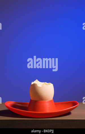 Ein gegessen Ei in rot Eierbecher auf blau. Stockfoto