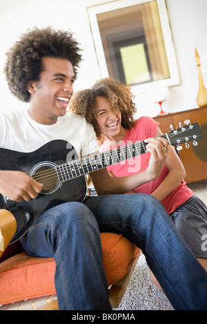 Frau, lachen, während Freund Gitarre spielt Stockfoto