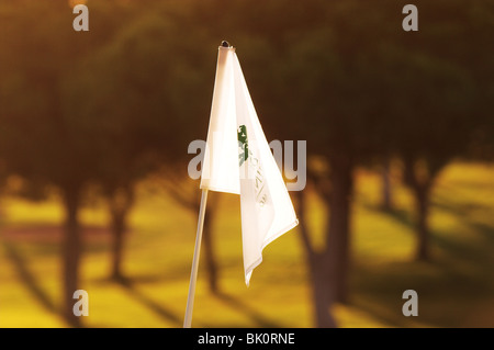 Weiße Golffahne, die beim Putten von Grün hinkt. Sonnenuntergang am späten Nachmittag ruhige Szene kein Wind Sommertag, Golfplatz an der sonnigen Algarve im Süden Portugals Stockfoto