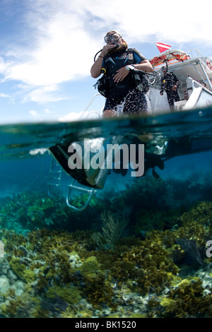 Scuba Diver gelangt Wasser vom Boot über großen Schritt Eintrag. Stockfoto