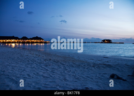 Ansicht von beleuchteten reetgedeckten Gebäuden auf Olhuveli Beach & Spa Resort, Malediven Stockfoto