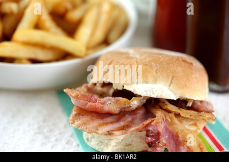 Ein frisch zubereitetes, gegrilltem oder gebratenem Speck in einem weißen Brötchen oder Bap mit einer Seite der Kartoffelchips oder Pommes Frites mit Keine Personen Stockfoto