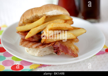 Ein frisch zubereitetes, gegrilltem oder gebratenem Speck in einem weißen Brötchen oder Bap mit einer Seite der Kartoffelchips oder Pommes Frites mit Keine Personen Stockfoto