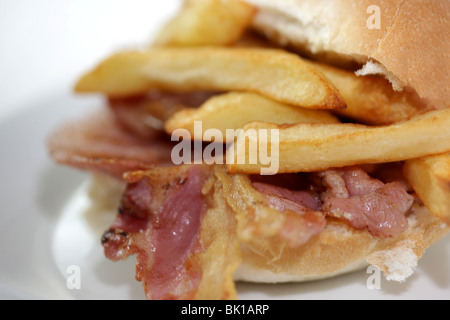 Ein frisch zubereitetes, gegrilltem oder gebratenem Speck in einem weißen Brötchen oder Bap mit einer Seite der Kartoffelchips oder Pommes Frites mit Keine Personen Stockfoto