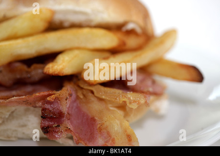 Ein frisch zubereitetes, gegrilltem oder gebratenem Speck in einem weißen Brötchen oder Bap mit einer Seite der Kartoffelchips oder Pommes Frites mit Keine Personen Stockfoto