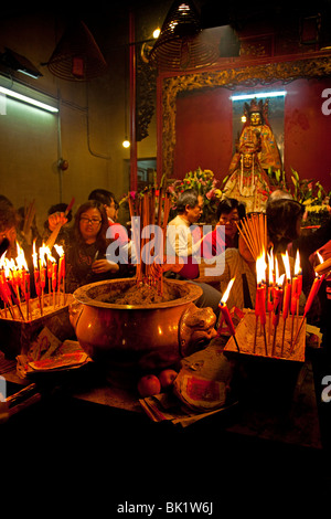 Der Man Mo Tempel Hong Kong, Räucherstäbchen Anzünden von Kerzen als Glücksbringer. Stockfoto