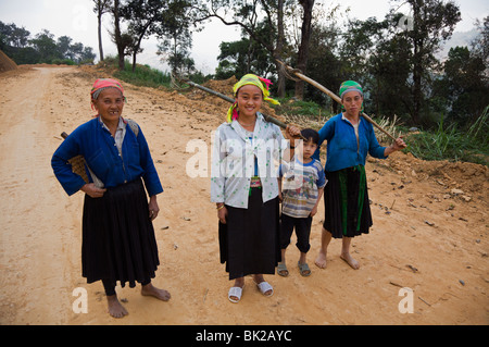 Blaue Hmong Frauen kommen zurück von der Arbeit in ihrem Bereich an der Straße zwischen Meo Vac und Bao Lac in Ha Giang Provinz Vietnam Stockfoto