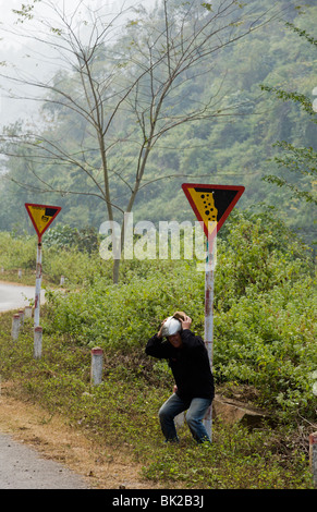 Mann durch kopfüber Achtung Scherz Schilder entlang Route 34 zwischen Bao Lac und Cao Bang in Nord-Vietnam Stockfoto