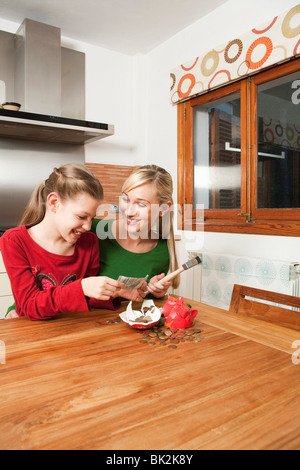 Mutter und Tochter knacken ein Sparschwein Stockfoto