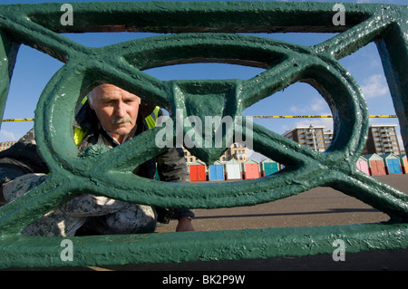 Ein älterer Mann malen die gusseisernen Geländer entlang der Strandpromenade von Brighton und Hove Stockfoto