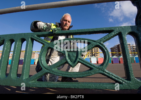 Ein älterer Mann malen die gusseisernen Geländer entlang der Strandpromenade von Brighton und Hove Stockfoto