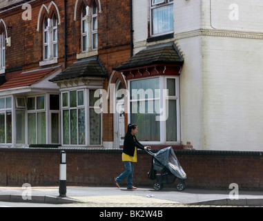 Kings Heath Birmingham West Midlands orientalische Frau schieben Kinderwagen vorbeigehen Häuser England Stockfoto