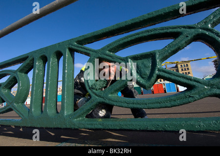 Ein Brighton und Hove Rat Arbeiter malen die Geländer direkt am Meer. Stockfoto