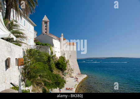 Schwimmer und Sonnenanbeter auf Felswand neben der Stadt Rab, Insel Rab, Kvarner Region, Kroatien, Europa Stockfoto