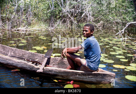 Ein Junge sitzt in einem ausgegraben Kanu mit einem Gewehr und hausgemachte Paddel, Belize Stockfoto