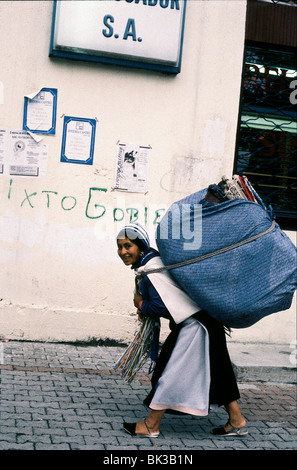 Eine Frau mit einem großen Bündel von Tuch Webereien auf dem Rücken, Ecuador Stockfoto