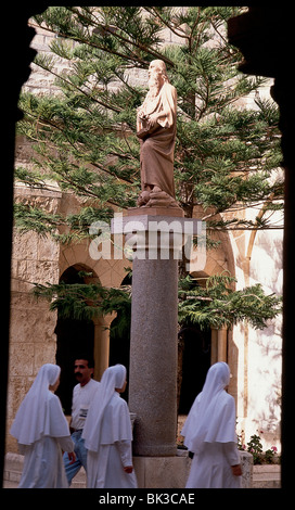 Römische katholische Nonnen in weißen Gewohnheiten zu Fuß durch die Statue des Heiligen Hieronymus (St. Hieronymus in lateinischer Sprache) außerhalb der Kirche des Hl. Stockfoto
