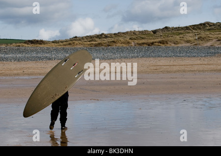 Eine Person, die ein Surfbrett auf Gwithian Towans Strand in Cornwall.  Foto von Gordon Scammell Stockfoto