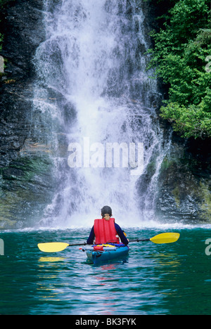 Kajak fahren unter einem Wasserfall entlang Endicott Arm Fjord in Southeast Alaska in der Tracy Arm Wildnis. Tongass National Forest. Stockfoto