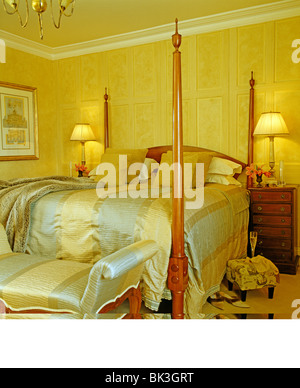 Blass blau + Creme gestreiften Seide gepolsterte Hocker und und passende Bettdecke im Bett im Schlafzimmer Gelb Land mit Lampen beleuchtet Stockfoto