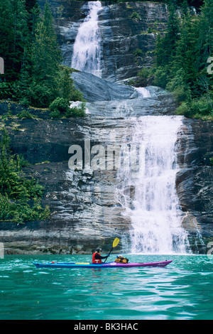 Kajak fahren unter einem Wasserfall entlang Endicott Arm Fjord in Southeast Alaska in der Tracy Arm Wildnis. Tongass National Forest. Stockfoto