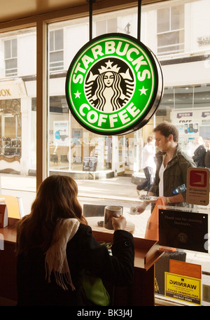 Ein Mädchen sitzt im Fenster der Starbucks Kaffee trinken, Cambridge, UK Stockfoto