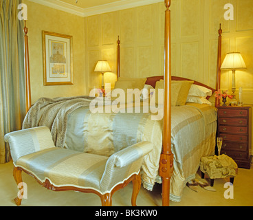 Blau + weiß gestreifter Seide gepolsterte Hocker und passende Bettdecke im Land Schlafzimmer mit brennenden Lampen auf Nachttischen Stockfoto
