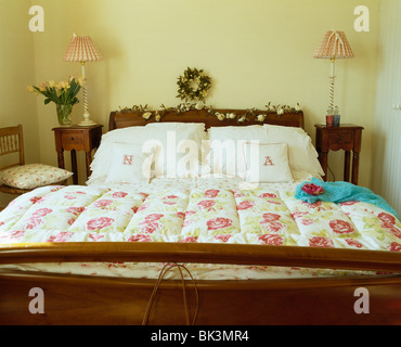 Quilt Rose gemustert und weißen Kissen auf Mahagoni Bett im Land Schlafzimmer mit Lampen an kleinen Tischen auf beiden Seiten des Bettes Stockfoto