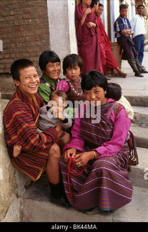 Frauen und Kinder tragen die traditionelle Kleidung der bunten Kiras (Damenkleider) und Ghos (Herren Roben) Bhutan Stockfoto