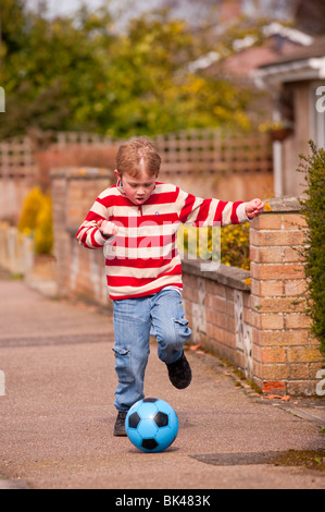 Ein MODEL Release Bild eines sechsjährigen Jungen spielen Fußball in die Steet im Vereinigten Königreich Stockfoto