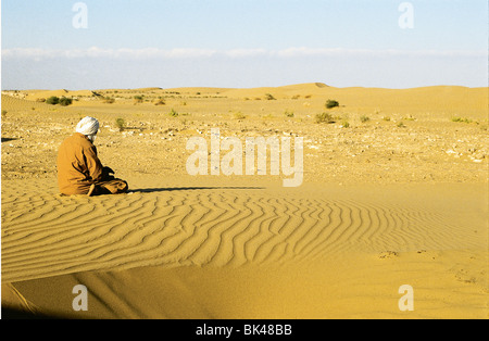 Ein Mann auf den Knien, abgewandt von der Sonne in der Sahara, LaYoune, Marokko Stockfoto