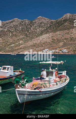 Fischer flickt sein Netz auf einem kleinen Boot in der geschützten Bucht von Kamares Stadt, Sifnos, Griechenland Stockfoto