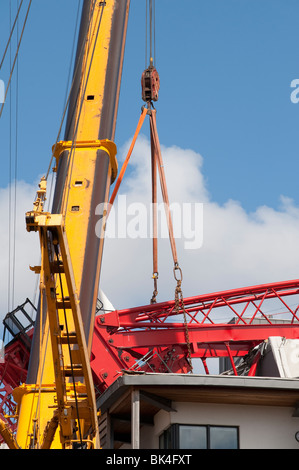 Turmdrehkran brach gefallenen auf Dach der Wohnblock wird von einem anderen Kran abgehoben Stockfoto