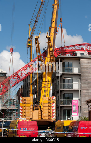 Turmdrehkran brach gefallenen auf Dach der Wohnblock wird von einem anderen Kran abgehoben Stockfoto